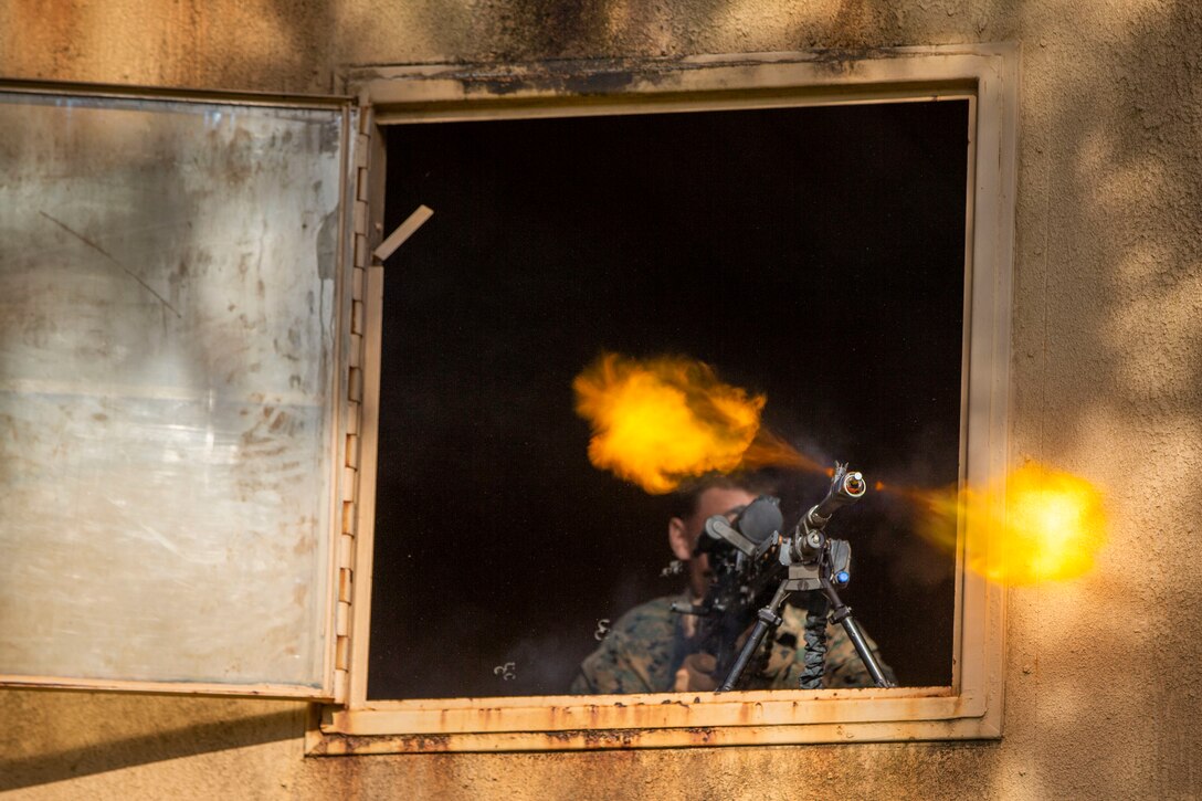 A Marine fires a weapon from a window of a structure.