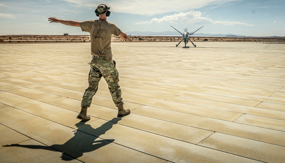 A U.S. Airman with the 163rd Attack Wing, California Air National Guard, directs an MQ-9 Reaper to a refueling point during Integrated Training Exercise 4-22 at Marine Corps Air-Ground Combat Center, Twenty-nine Palms, Calif. on July 20th, 2022. The MQ-9 Reaper received fuel via aviation delivered ground refueling from an MV-22 Osprey with Marine Medium Tiltrotor Squadron 764, marking the first time the MQ-9 received fuel from a joint asset and the first time an Air National Guard MQ-9 received fuel from another aircraft. The MQ-9 Reaper provided close air support to Marine Air-Ground Task Force 23 during its execution of the fire support coordination exercise of ITX as the Marine Corps Reserve continues to work to integrate with sister services in preparation for future operations.