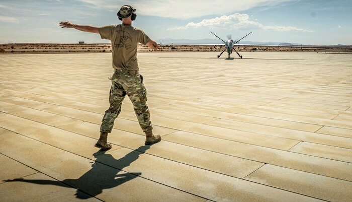 A U.S. Airman with the 163rd Attack Wing, California Air National Guard, directs an MQ-9 Reaper to a refueling point during Integrated Training Exercise 4-22 at Marine Corps Air-Ground Combat Center, Twenty-nine Palms, Calif. on July 20th, 2022. The MQ-9 Reaper received fuel via aviation delivered ground refueling from an MV-22 Osprey with Marine Medium Tiltrotor Squadron 764, marking the first time the MQ-9 received fuel from a joint asset and the first time an Air National Guard MQ-9 received fuel from another aircraft. The MQ-9 Reaper provided close air support to Marine Air-Ground Task Force 23 during its execution of the fire support coordination exercise of ITX as the Marine Corps Reserve continues to work to integrate with sister services in preparation for future operations.
