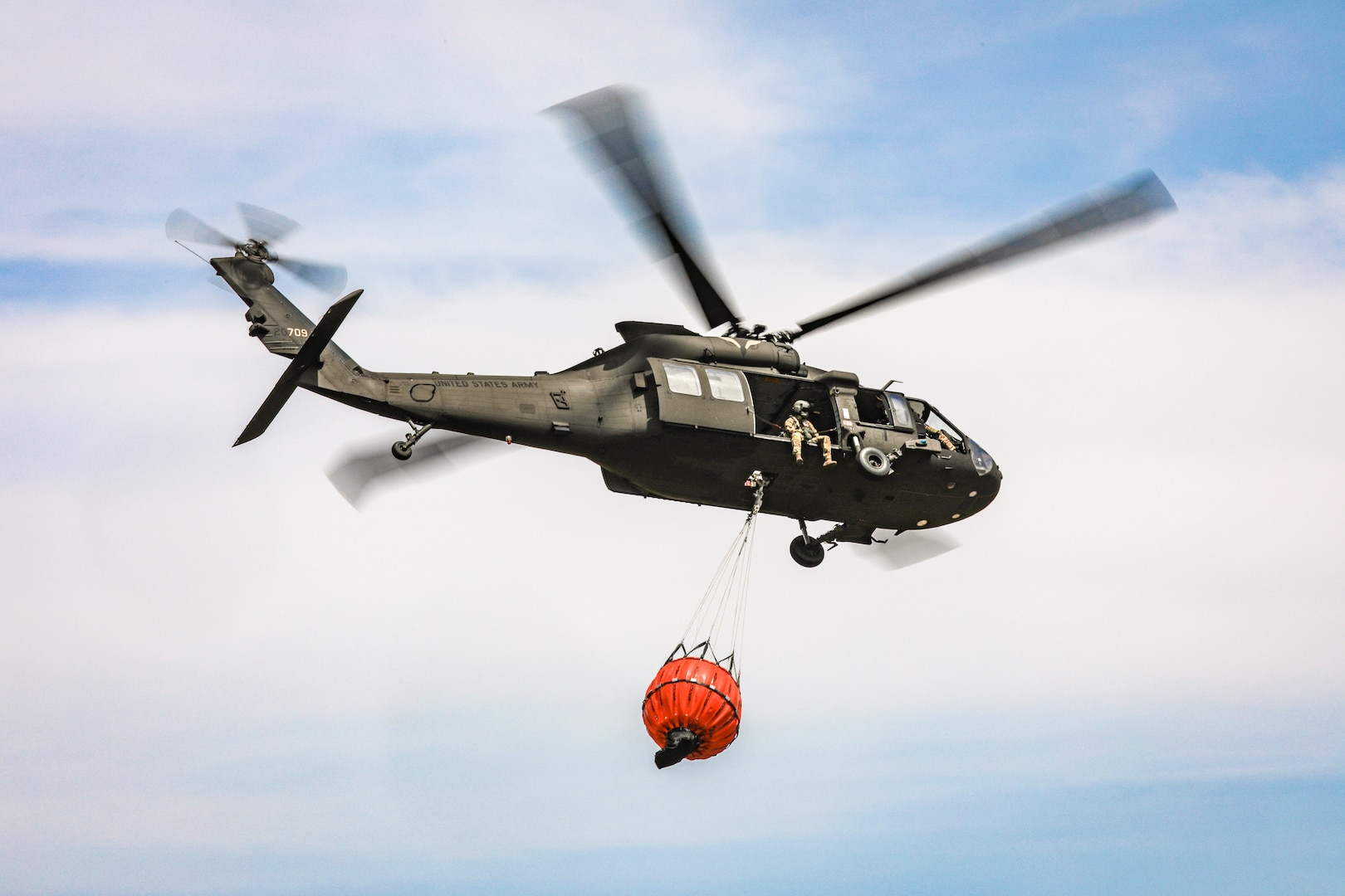 An Oklahoma Army National Guard UH-60 Black Hawk flies over the 702 Fire in Blaine County, Oklahoma, after dropping more than 600 gallons of water on the fire, July 16, 2022. The Oklahoma National Guard is supporting the Oklahoma Forestry Services and local fire departments from the air using a UH-60 Black Hawk and a LUH-72 Lakota.