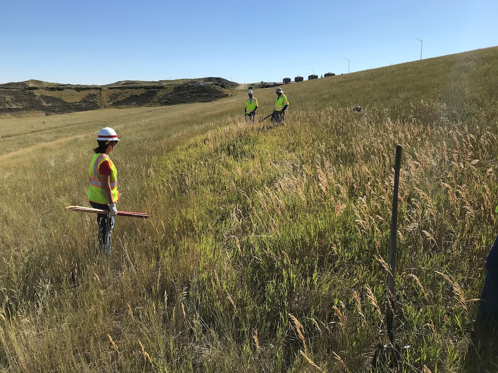 Dam safety inspectors walk the earthen embankment of Fort Peck Dam.