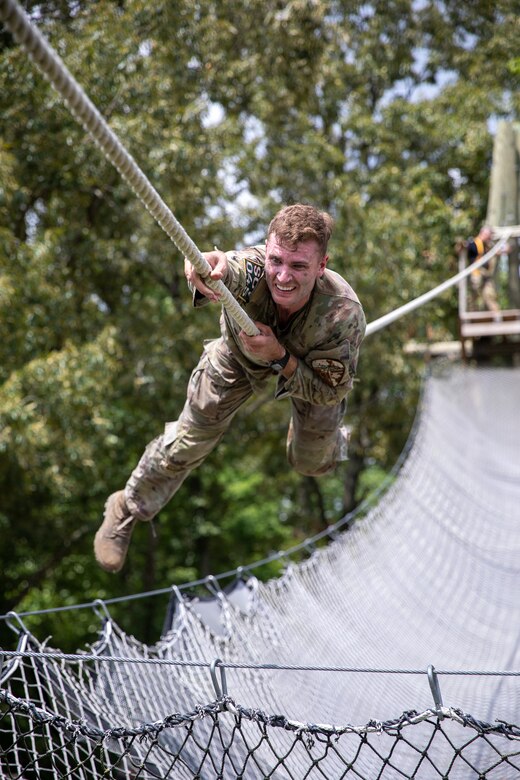 A soldier crosses a rope obstacle during an obstacle course.