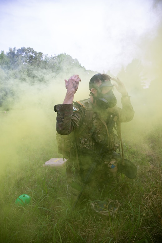 A soldier wearing a protective gas mask uses the arm signal for gas or chemical attack.