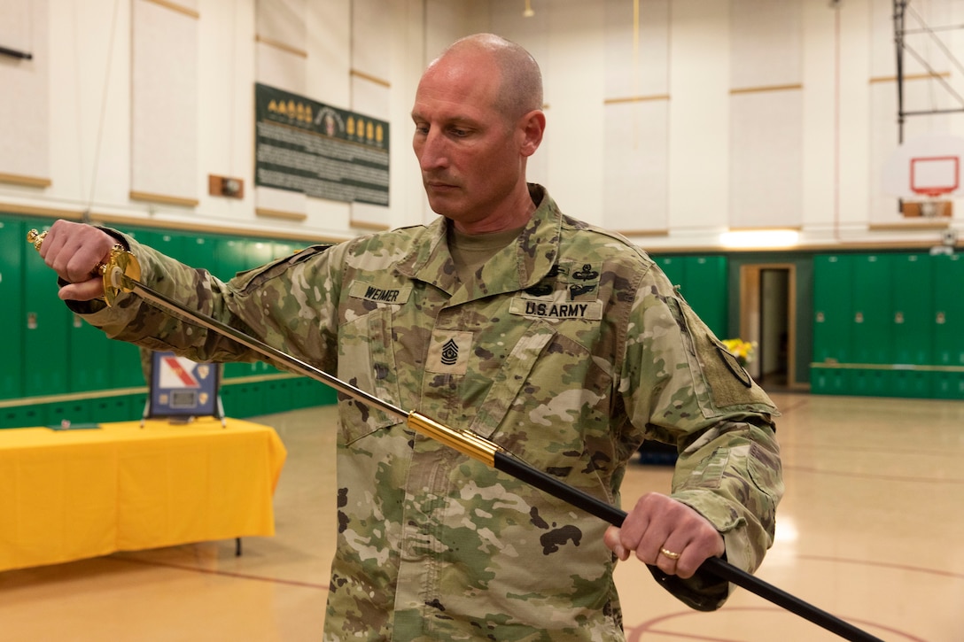 Alaska Army National Guard Command Sgt. Maj. Ryan Weimer unsheathes the sword during a change of responsibility ceremony at the Alcantra Armory in Wasilla, Alaska, Aug. 1, 2022. Command Sgt. Maj. Julie Small relinquished responsibility as the 297th Regional Support Group's Senior Enlisted Leader to Weimer. (Alaska National Guard photo by Victoria Granado)