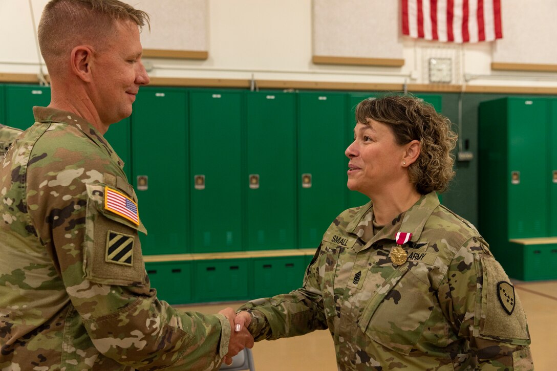Alaska Army National Guard Col. Thomas Elmore presents a meritorious service medal to Command Sgt. Maj. Julie Small during a change of responsibility ceremony at the Alcantra Armory in Wasilla, Alaska, Aug. 1, 2022. Small relinquished responsibility as the 297th Regional Support Group's Senior Enlisted Leader to Command Sgt. Maj. Ryan Weimer. (Alaska National Guard photo by Victoria Granado)