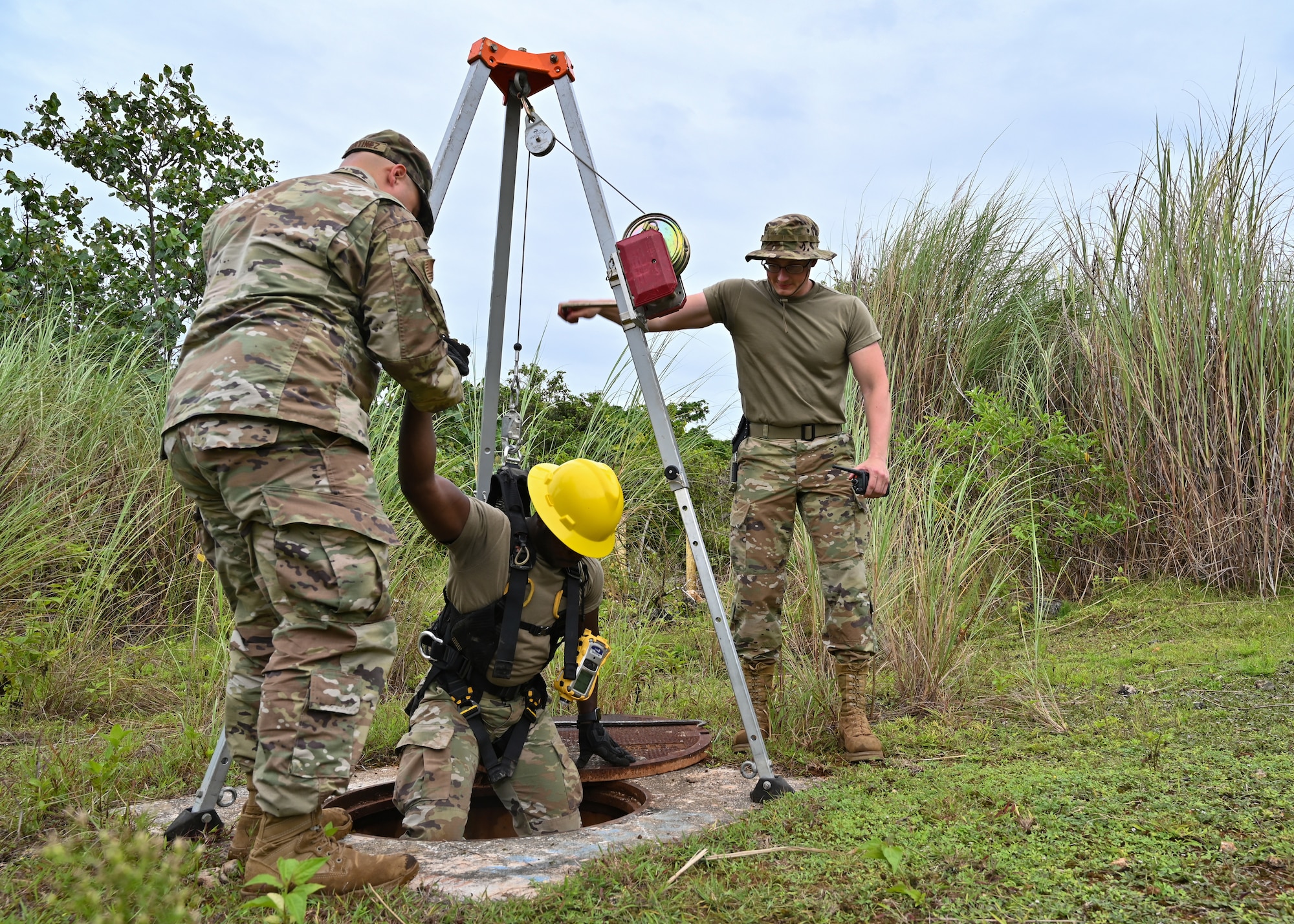 U.S. Air National Guard Master Sgt. Nicholas Martinez, 205th Engineering Installation Squadron first sergeant, and Staff Sgt. Zachery Muth, 210th Engineering Installation Squadron cable antenna systems craftsman, assist Airman 1st Class Abu Bangura, 205 EIS cable antenna systems apprentice, exit a telecommunications maintenance hole on Andersen Air Force Base, Guam, July 26, 2022. U.S. Air National Guard engineering installation squadrons from across the country have integrated as one unit to work alongside the 36th Communications Squadron to refresh records and repair infrastructure on Andersen AFB. (U.S. Air Force photo by Airman 1st Class Lauren Clevenger)