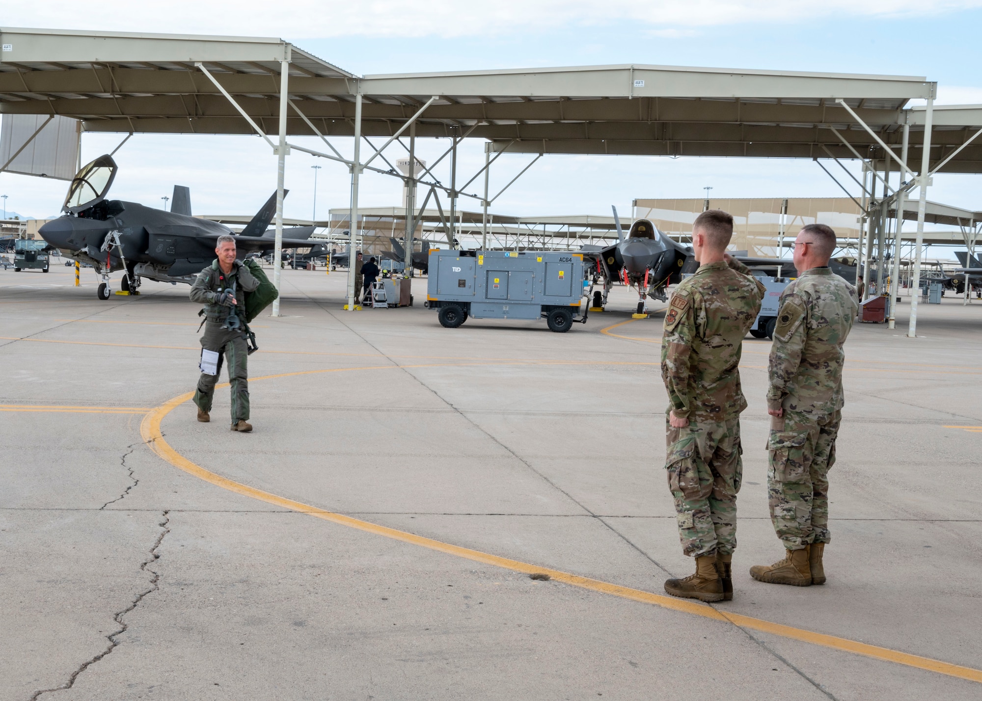 U.S. Air Force Brig. Gen. Gregory Kreuder, 56th Fighter Wing commander, steps out to the flight line to meet CMSgt Donald Price, 61st Aircraft Maintenance Unit senior enlisted leader, and Senior Airman Aaron Robosky, 61st Aircraft Maintenance Unit dedicated crew chief, for his “fini” flight July 25, 2022, at Luke Air Force Base, Arizona.