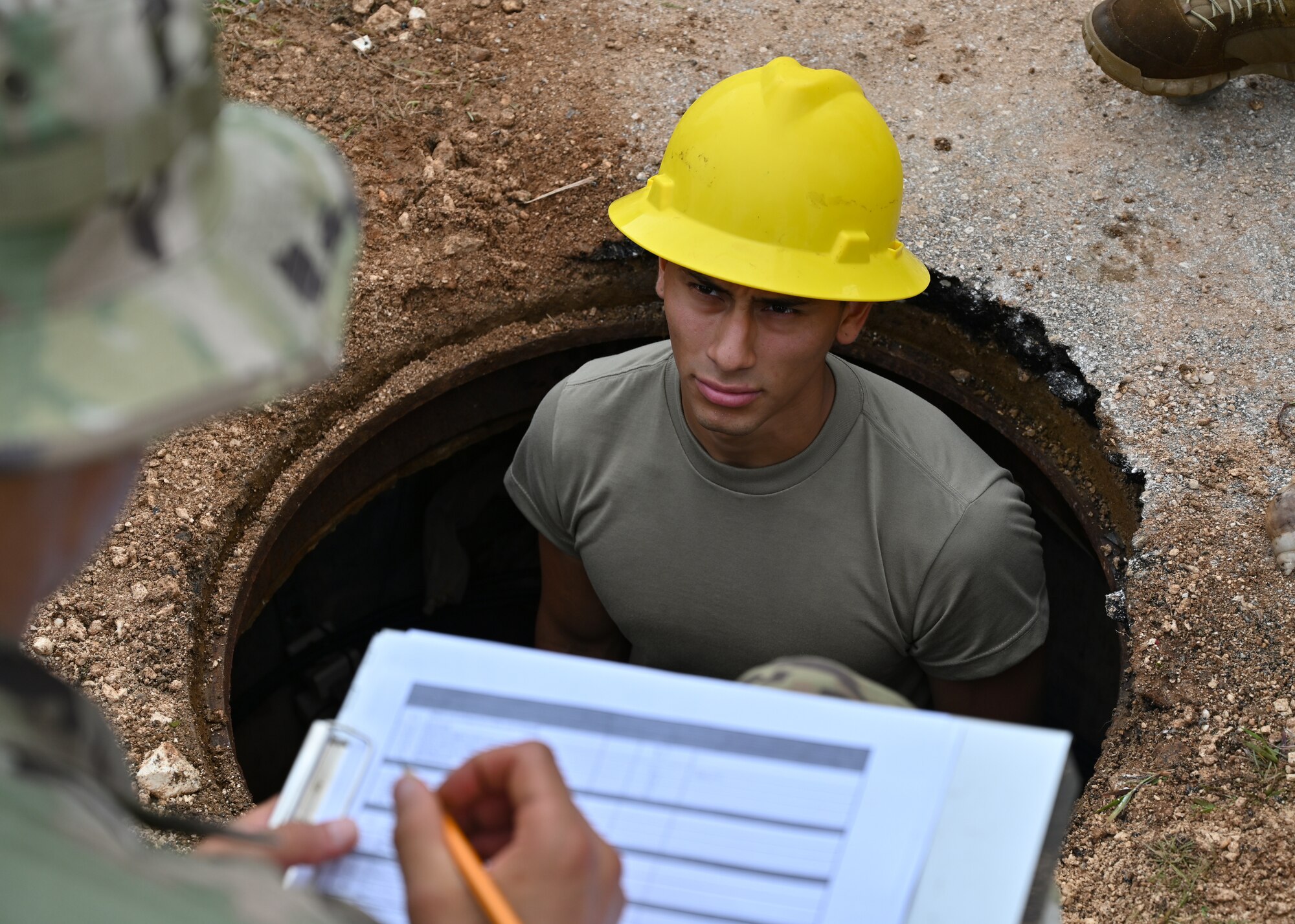 U.S. Air National Guard Senior Airman Ruben Flores, 212th Engineering Installation Squadron radar, airfield and weather systems journeyman, relays the telecommunication cables seen in a telecommunications maintenance hole to another team member on Andersen Air Force Base, Guam, July 26, 2022. Radar, airfield and weather system journeymen are responsible for installing, maintaining and repairing fixed and mobile radar, navigational aids, weather systems and radios. (U.S. Air Force photo by Airman 1st Class Lauren Clevenger)