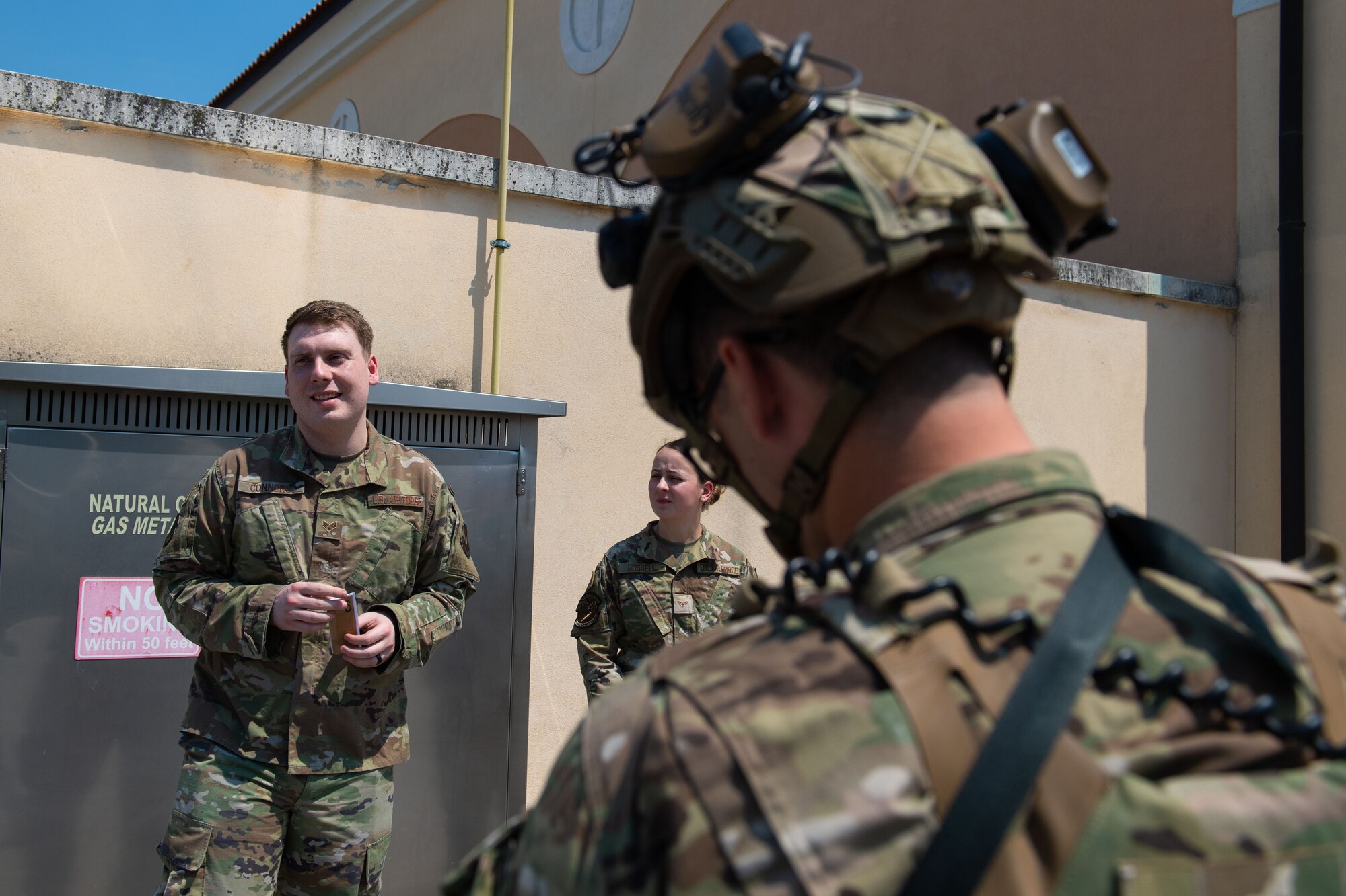 Senior Airman Devon Connors, 31st Force Support Squadron postal clerk and Airman 1st Class Sarah Russell, 175th Wing Air National Guard, personnelist, brief U.S. Air Force Master Sgt. Jordan Whitlock, 31st Security Forces Squadron flight chief, upon discovering a simulated suspicious package during an exercise at Aviano Air Base, Italy, July 21, 2022. Communication between the post office personnel and responding units is key to a quick and effective response for returning safety to Aviano AB. (U.S. Air Force photo by Staff Sgt. Douglas Lorance)