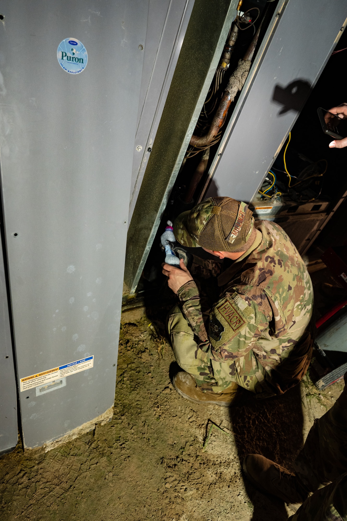U.S. Air Force Staff Sgt. Robert Milliner a heating ventilation and air conditioning airman from the 379th Expeditionary Civil Engineer Squadron, uses a water bottle with a foaming agent to find a leak in an air conditioning unit, July 29, 2022 at Al Udeid Air Base, Qatar. Once the leak was found the team took action to seal it and brought the unit back into working order. (U.S. Air Force photo by Staff Sgt. Dana Tourtellotte)