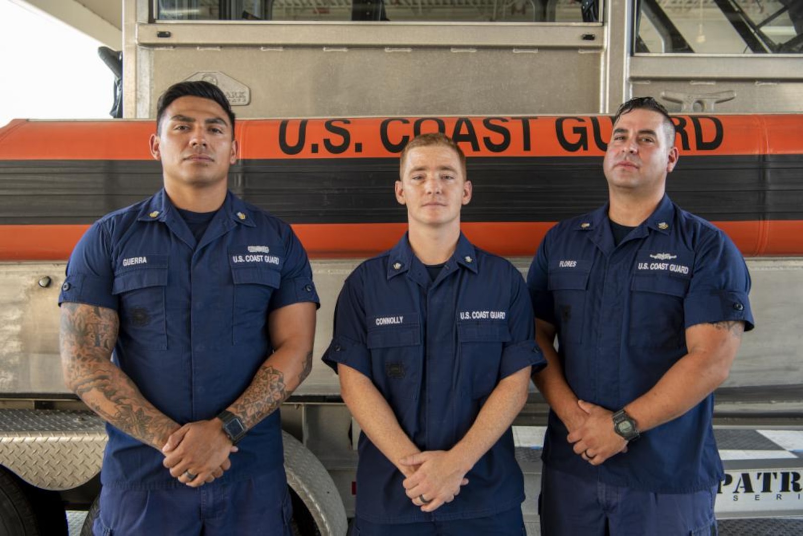 Petty Officer 2nd Class Jarrett Guerra, Petty Officer 3rd Class Corey Connolly and Petty Officer 2nd Class Jake Flores, members of Coast Guard Maritime Safety & Security Team Houston, pose for a photo in the unit’s boat shed in Houston, Texas, July 14, 2022. While deployed to the Rio Grande on June 2, 2022, Guerra, Connolly and Flores saved two adult females and a 1-year-old boy from drowning in the river. (U.S. Coast Guard photo by Petty Officer 1st Class Corinne Zilnicki)