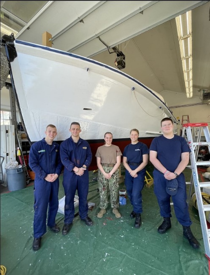 Chatham, Massachusetts - Massachusetts Maritime Academy Auxiliary University Program (AUP) Cadets Mitchell Campbell, Jacob Bolles, Alexa Smith, Abigail LeLievre, and Cole Francavilla stand in front of retired Motor Life Boat CG 36500 during spring commissioning work. The cadets learned more about the history of the boat and the Pendleton Rescue made famous by the Disney movie, "The Finest Hours” and then painted the entire hull including the bottom and topsides. U.S. Coast Guard Auxiliary Photo by Auxiliarist Lisa Goodwin.