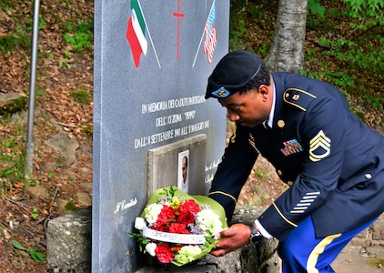 The Army Field Support Battalion-Africa intelligence and operations noncommissioned officer in charge, Sgt. 1st Class Tehran Jones, lays flowers at the base of the memorial site for Manrico Ducceschi, also known as Pippo, during a Italian-American commemorative ceremony in Pianaccina Pian di Novello, July 31. “I will continue to support this ceremony as long as I'm stationed here,” said Jones. (Photo by Elena Baladelli)