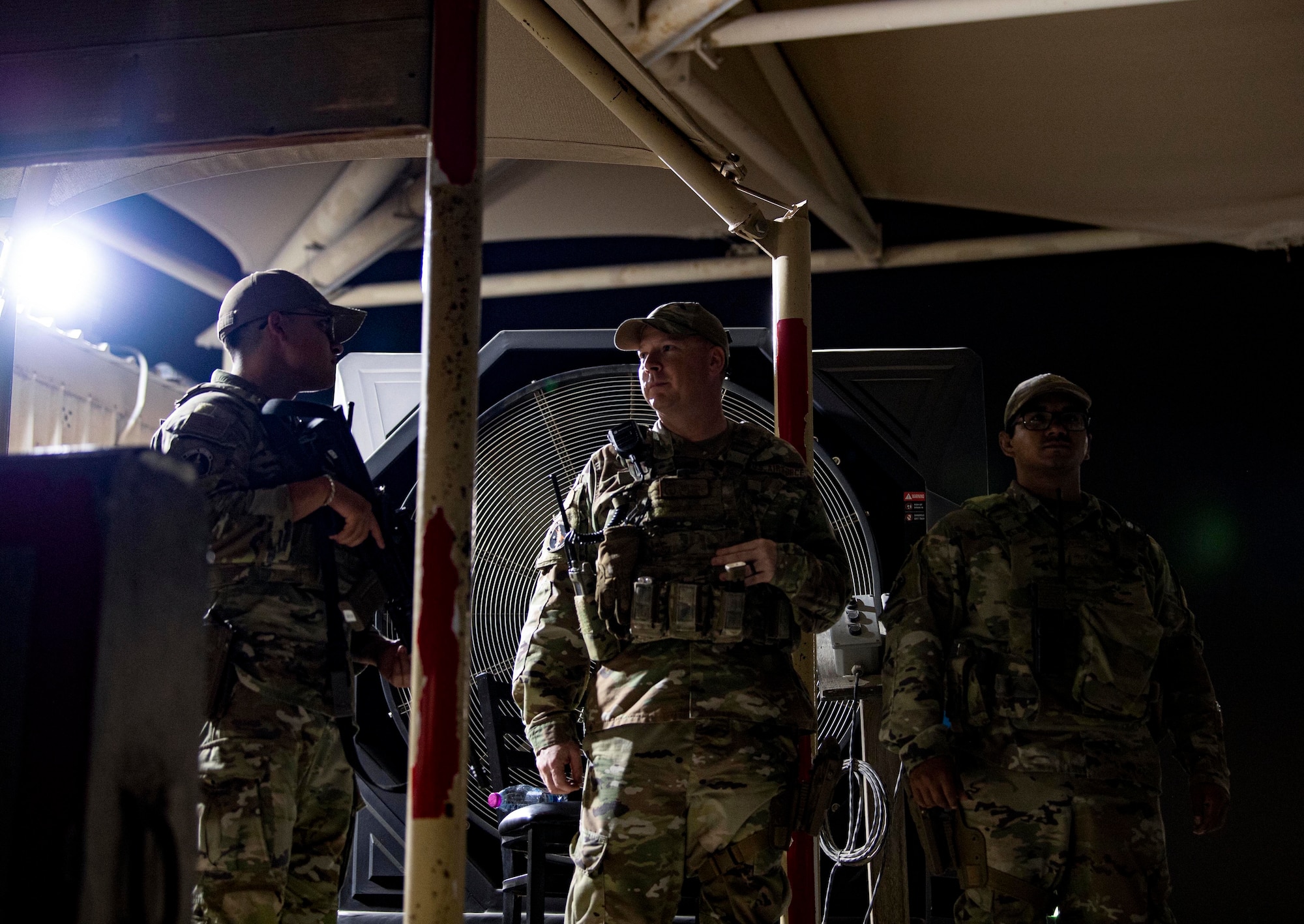 U.S. Air Force Tech. Sgt. Ken Paul (center), 379th Expeditionary Security Forces Squadron, checks in with Defenders at an entry control point July 25, 2022 at Al Udeid Air Base. ESFS Defenders maintain base defense at all hours day and night. (U.S. Air National Guard photo by Master. Sgt. Michael J. Kelly)