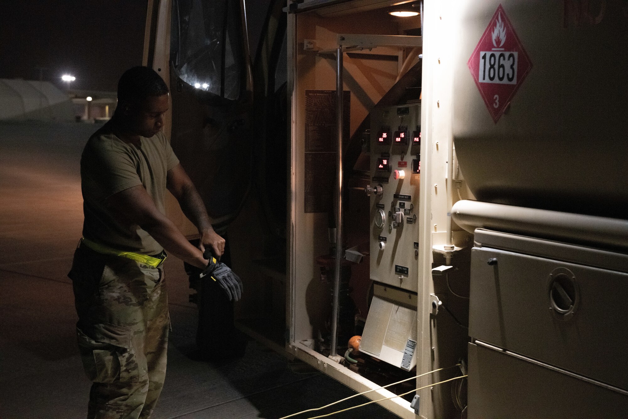 U.S. Air Force Senior Airman Derik Pete, a distribution operator from the 379th Expeditionary Logistics Readiness Squadron, dons gloves prior to refueling a C-130 on Al Udeid Air Base, Qatar, July 18, 2022. Petroleum, oil and lubricants is the department responsible for the distribution of different kinds of fuels. (U.S. Air National Guard photo by Airman 1st Class Constantine Bambakidis)