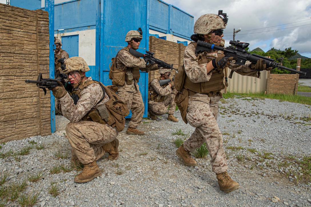 Marines, kneeling and standing, point weapons in various directions.