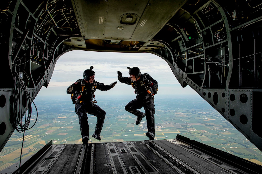 Two soldiers jump backwards from an aircraft in flight.