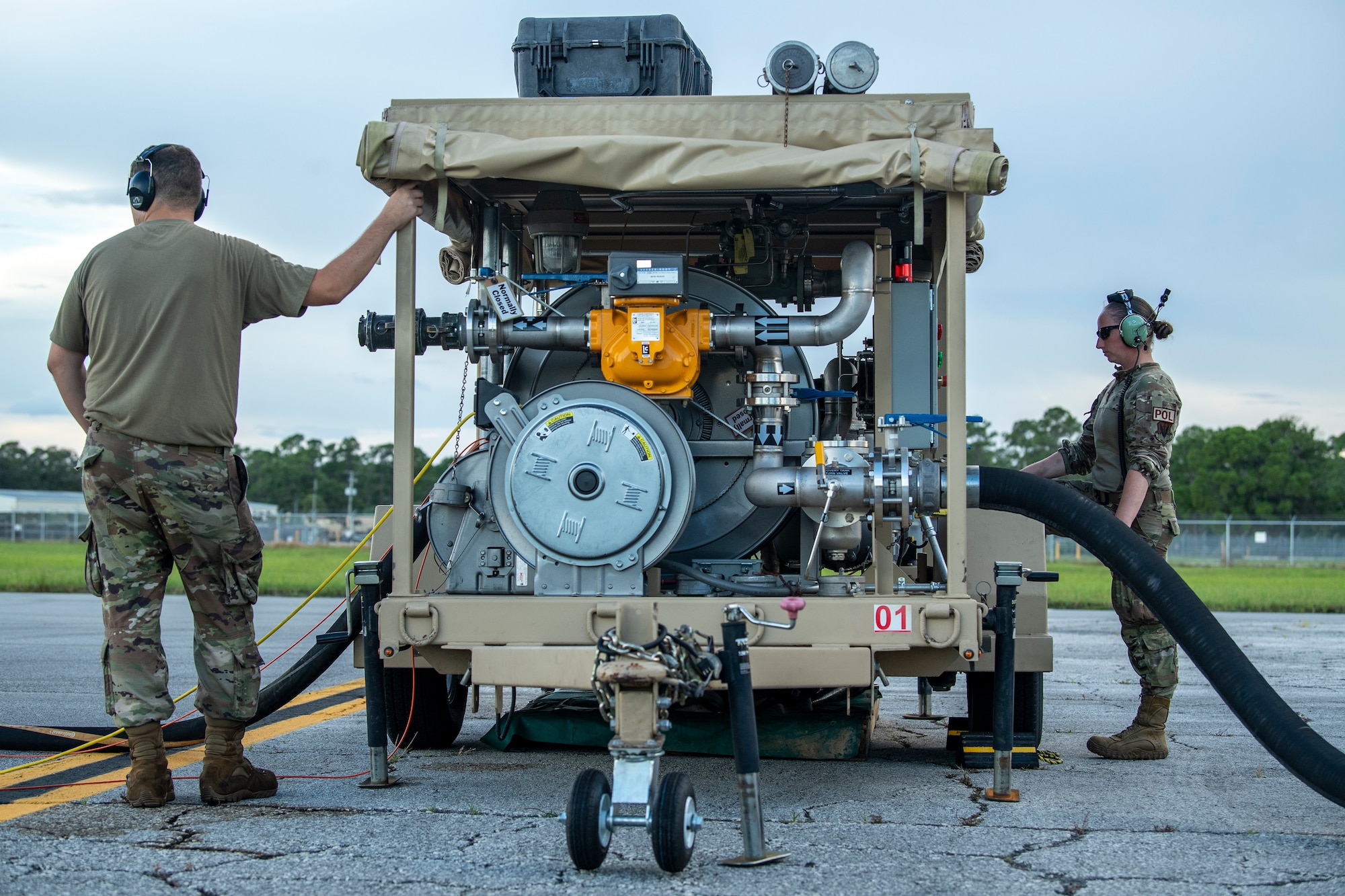 Two Airmen utilize a strategic aircraft refueling cart to refuel an aircraft