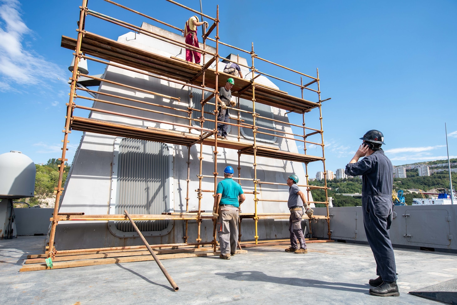 Electronics Technician 3rd Class Alex Lare, right, from King George, Virginia, assigned to the San Antonio-class amphibious transport dock ship USS Arlington (LPD 24), supervises contractors during preservation work for mid-deployment voyage repairs in Rijeka, Croatia, July 6, 2022.