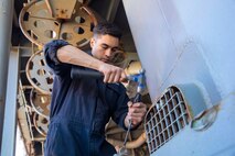 U.S. Navy Culinary Specialist Seaman   Isaiah Perales replaces a watertight door during mid-deployment voyage repairs, July 12, 2022.