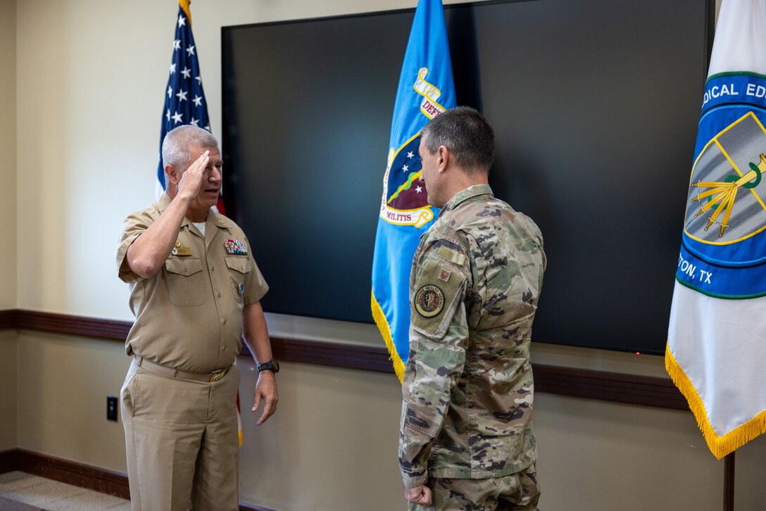 Navy Capt. Thomas Herzig, outgoing Commandant of the Medical Education and Training Campus (METC), is relieved by Air Force Col. David Walmsley during a low-key ceremony held July 21.