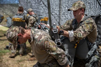 Staff Sgt. Brock Williams (left), a member of the Tactical Air Control Party with the 146th Air Support Operations Squadron, 137th Special Operations Wing, Oklahoma Air National Guard, dons his parachute with the aid of another Airman in preparation for a high performance jump from a C-130 “Hercules” at Fort Chaffee, Arkansas, July 23, 2022. The Airmen participated in airborne operations with Soldiers from 2nd Battalion, 134th Infantry Regiment, 45th Infantry Brigade Combat Team, Nebraska Army National Guard. (Oklahoma National Guard photo by Pfc. Haden Tolbert)