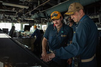 Cmdr. James Hagerty, right, commanding officer of USS Bainbridge (DDG 96), and Lt. j.g. Joseph Trybus discuss navigation in the ship's pilothouse in Civitavecchia, Italy.