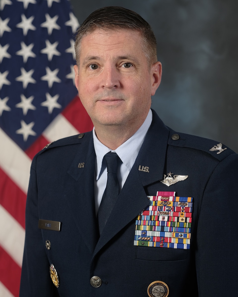 photo of USAF Airman standing in front of U.S. flag