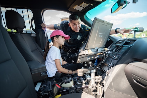 law enforcement officer shows child police equipment