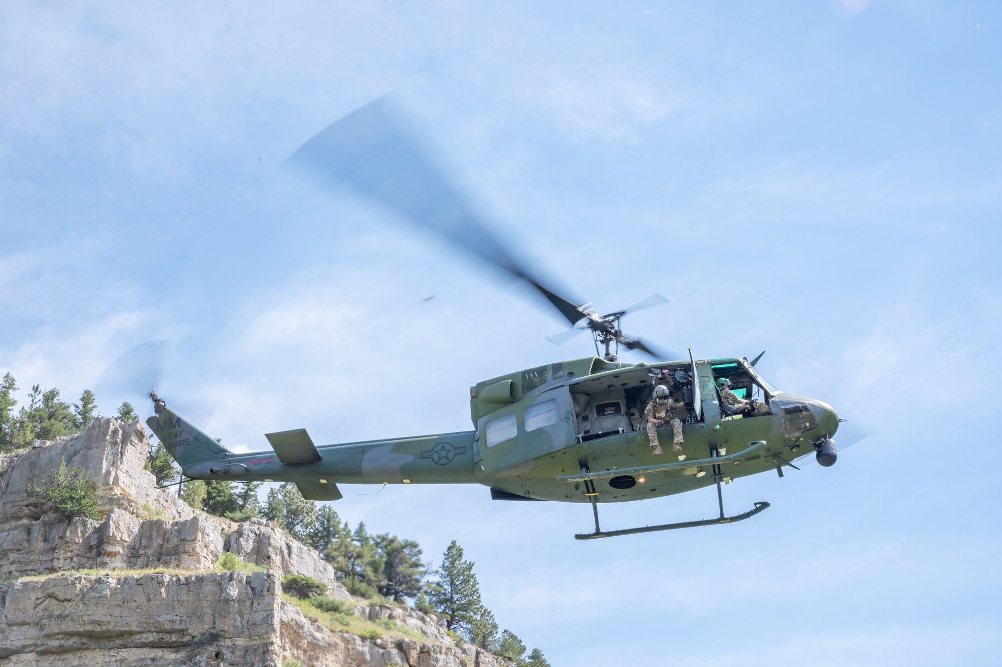 Tech. Sgt. Alex Landers, 40th Helicopter Squadron special missions aviator flight engineer, sits on the edge of a UH-N1 Huey helicopter Aug. 2, 2022, above Sluice Boxes State Park, Mont.
