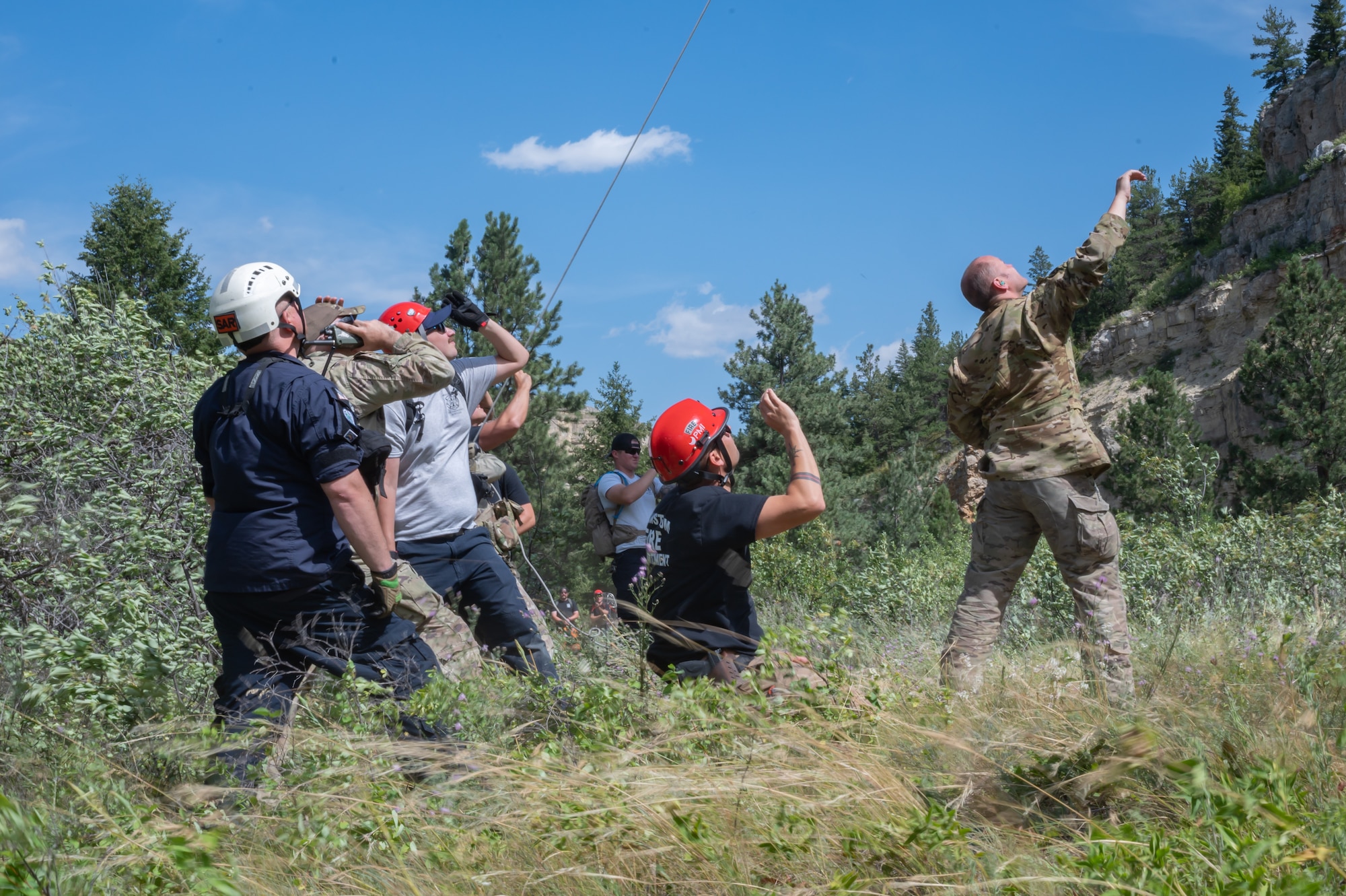 Malmstrom Air Force Base Airmen look up at a UH-N1 Huey helicopter during a search and rescue exercise Aug. 2, 2022, in Sluice Boxes State Park, Mont.