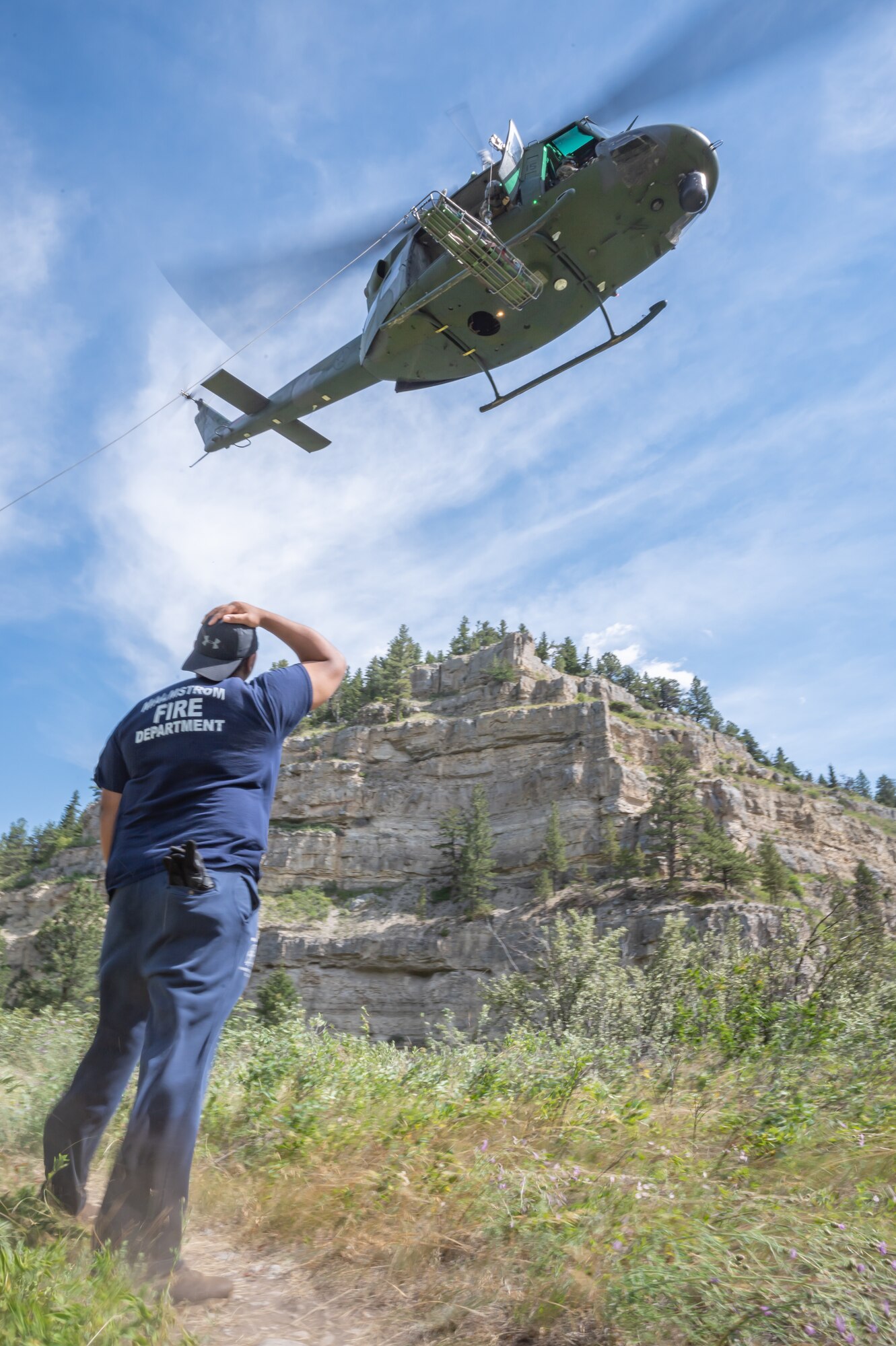 Tech. Sgt. Lee Mathews, 341st Civil Engineer Squadron Fire Department NCO in charge of the emergency communications center, looks up at a UH-N1 Huey helicopter Aug. 2, 2022, in Sluice Boxes State Park, Mont.