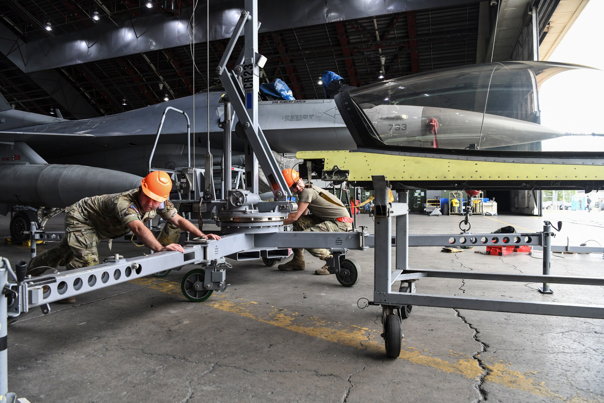 Military members working with a crane on a jet.