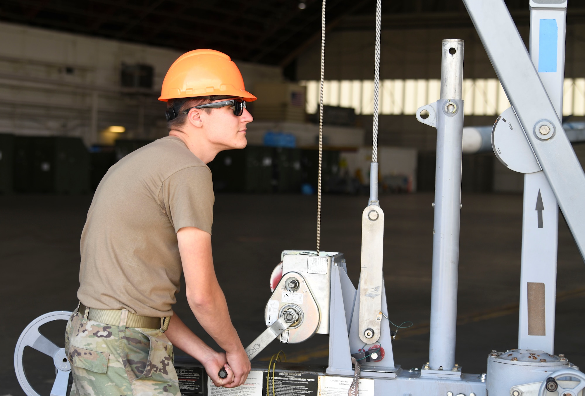 A Military member working with a crane on a jet.