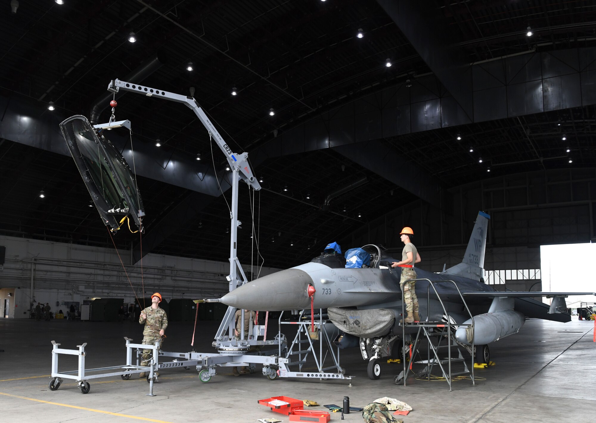 Military members working with a crane on a military jet