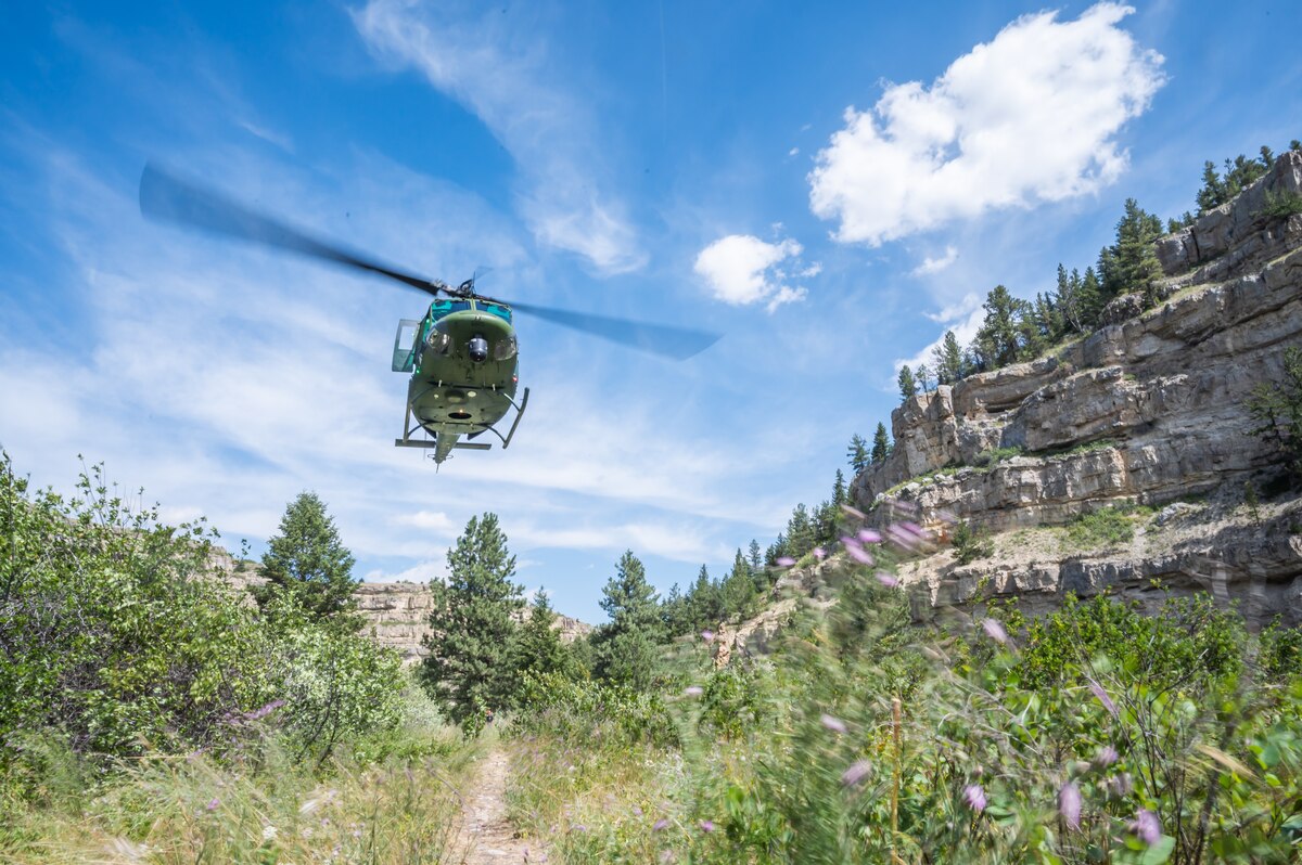 A UH-N1 Huey helicopter flies above the Sluice Boxes State Park trail during a search and rescue exercise Aug. 2, 2022, in Cascade County, Mont.