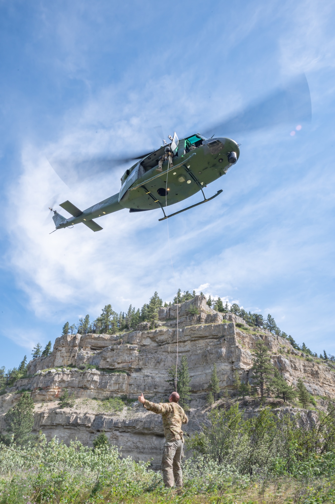 Staff Sgt. Joel Hogan, 40th Helicopter Squadron special missions aviator instructor flight engineer, holds a tag line leading to a UH-N1 Huey helicopter Aug. 2, 2022, in Sluice Boxes State Park, Mont.