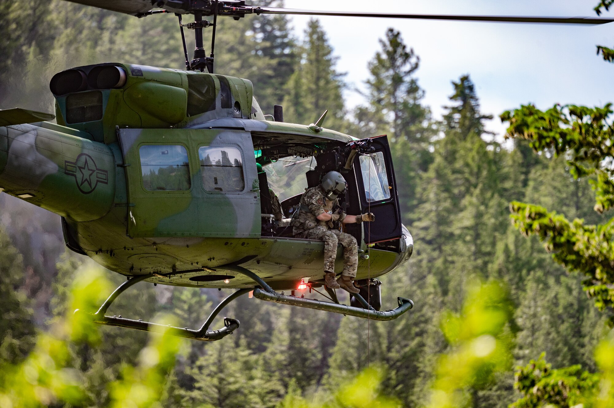 Tech. Sgt. Alex Landers, 40st Helicopter Squadron flight engineer, lowers the flight doctor out of an UH-N1 Huey during a search and rescue exercise August 3, 2022, in Sluice Boxes State Park.