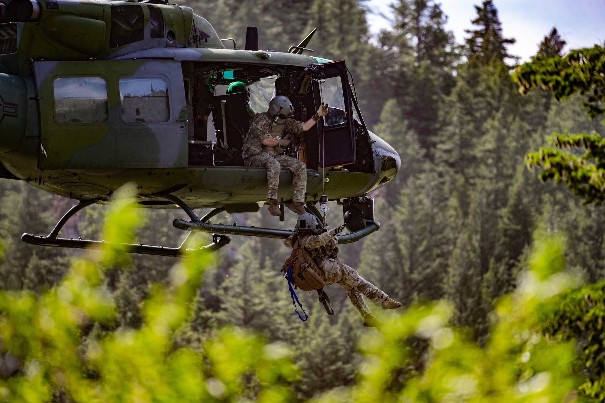 Tech. Sgt. Alex Landers, 40st Helicopter Squadron flight engineer, lowers Maj. Joyanne Tesei, 341st Medical Group flight doctor, out of an UH-N1 Huey during a search and rescue exercise August 3, 2022, in Sluice Boxes State Park.