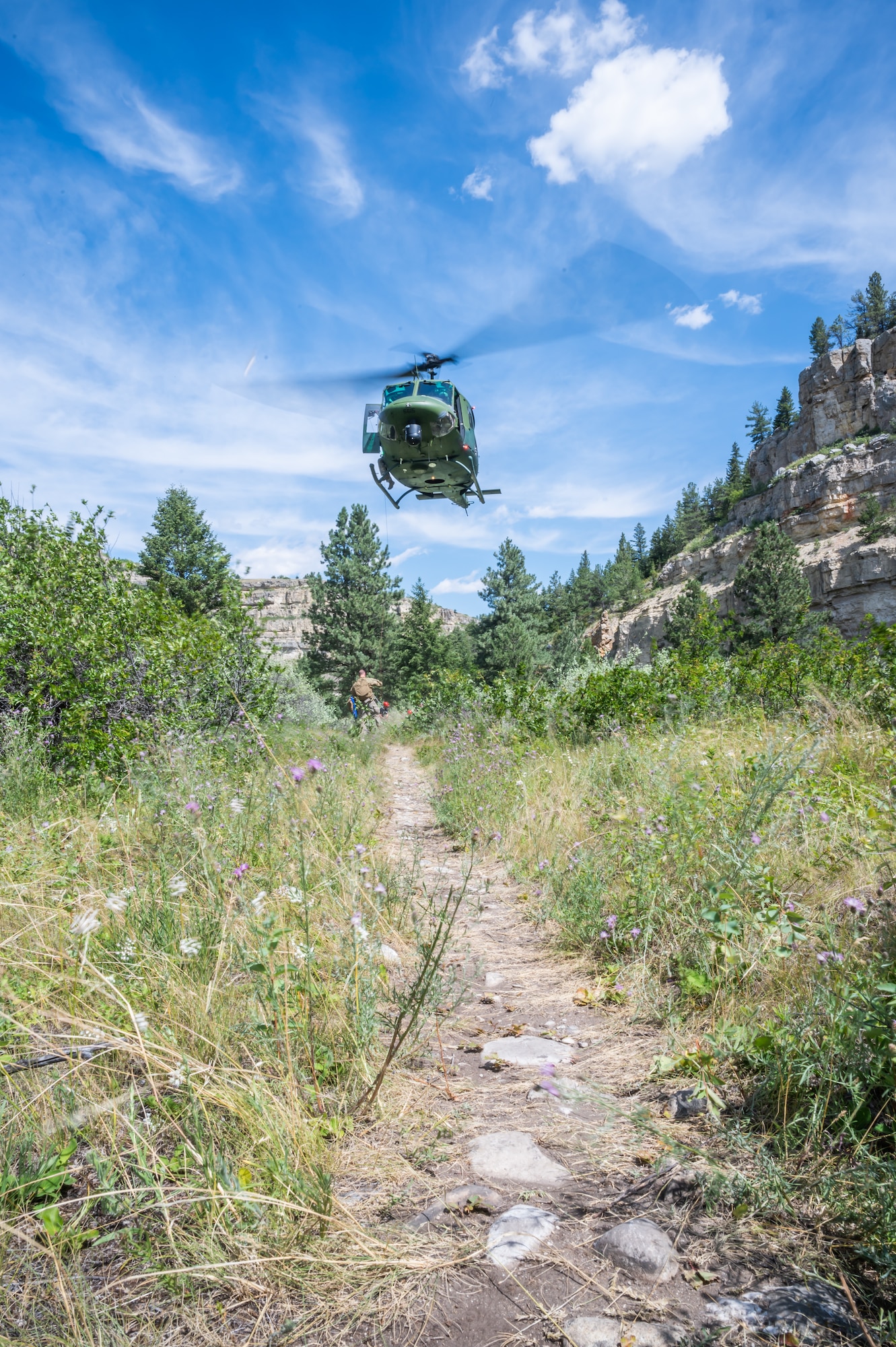 A UH-N1 Huey helicopter flies above the Sluice Boxes State Park trail during a search and rescue exercise Aug. 2, 2022, in Cascade County, Mont.