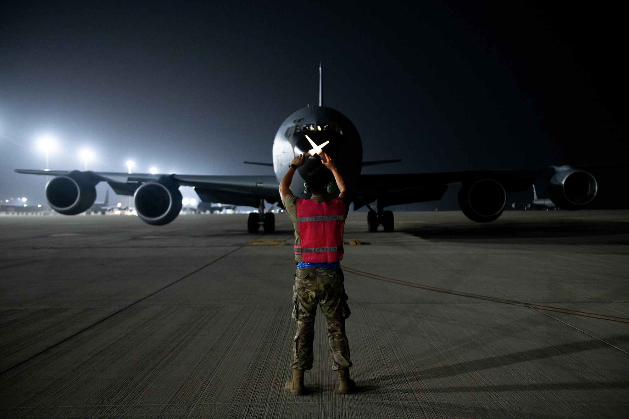 U.S. Air Force Senior Airman Jesse Lookingglass, a KC-135 maintainer with the 379th Expeditionary Air Maintenance Squadron, guides an aircraft into a parking spot on Al Udeid Air Base, Qatar, Aug. 1, 2022. After landing, the aircraft taxis to it’s spot on the ramp, where any required maintenance is performed. (U.S. Air National Guard photo by Airman 1st Class Constantine Bambakidis)