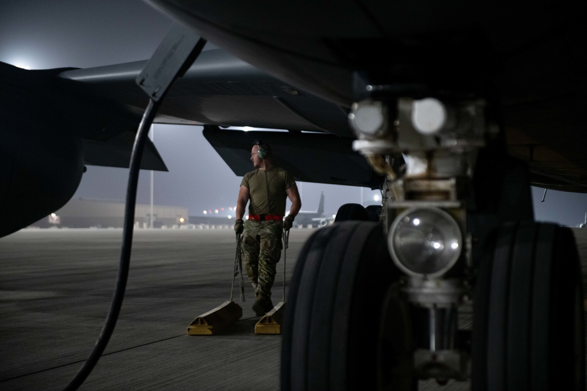U.S. Air Force Airman 1st Class Nick Lukacsina, a KC-135 maintainer with the 379th Expeditionary Air Maintenance Squadron, drags tire chalks to a KC-135’s rear landing gear on Al Udeid Air Base, Qatar, Aug. 1, 2022. Tire chalks help stabilize the aircraft once it’s parked on the ramp. (U.S. Air National Guard photo by Airman 1st Class Constantine Bambakidis)