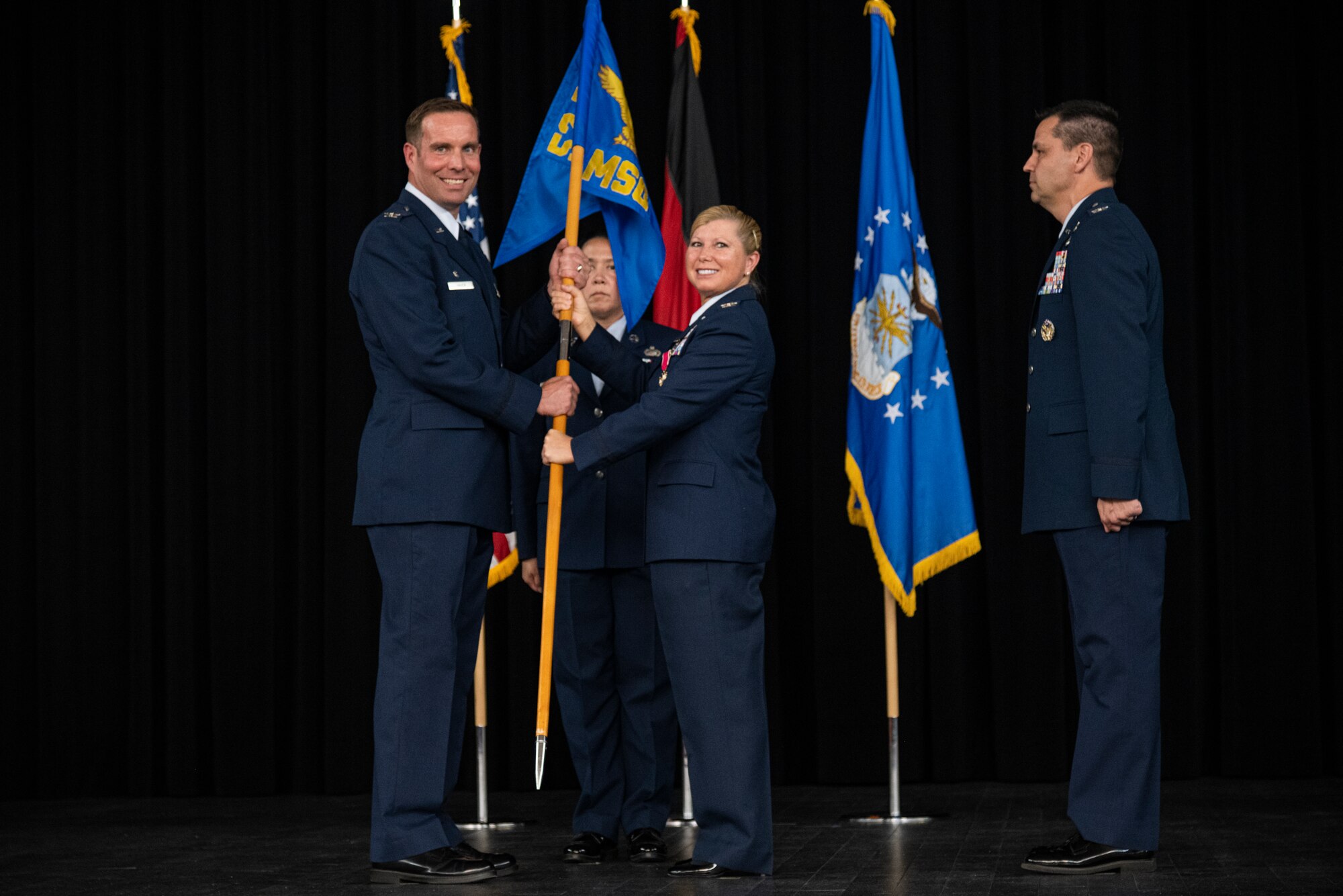 Two service members holding a military squadron flag