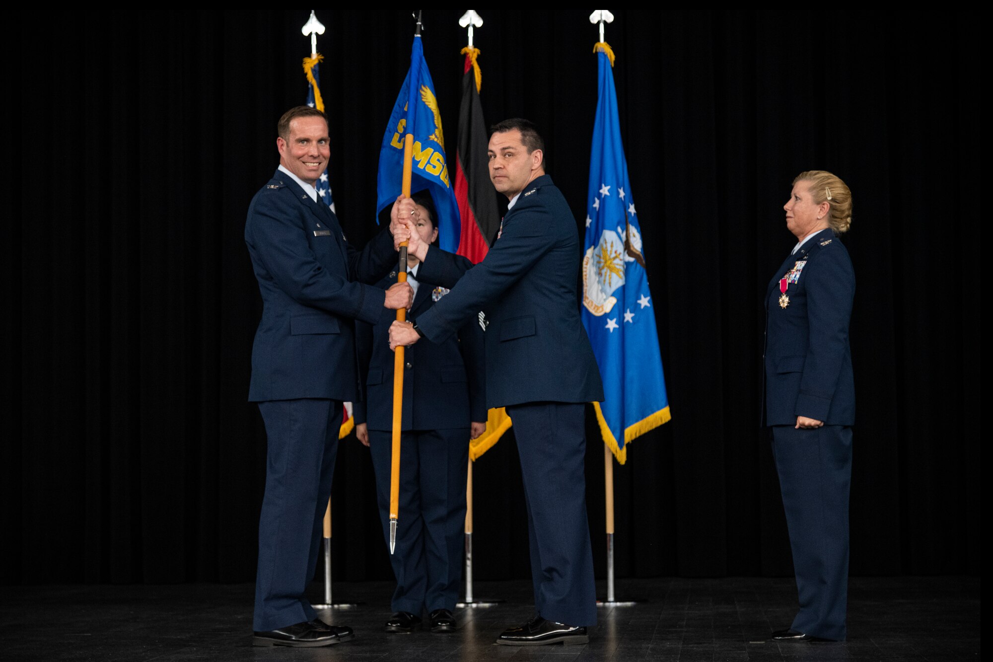 Two service members holding a flag representing a military squadron
