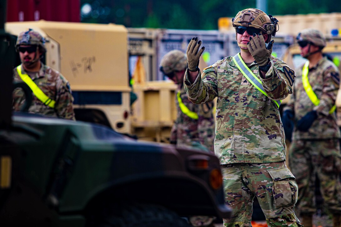 A soldier holds his hands up as he gives directions.