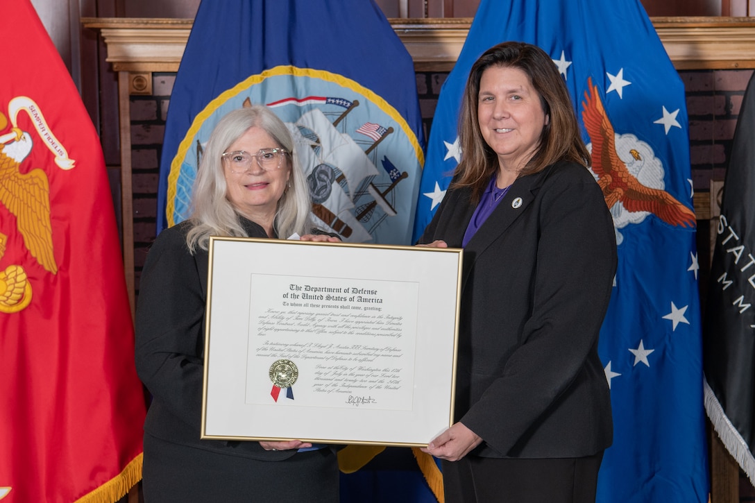 two women in business attire holding certificate
