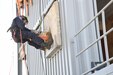 Soldier rappels on side of building with dummy attached simulating a casualty