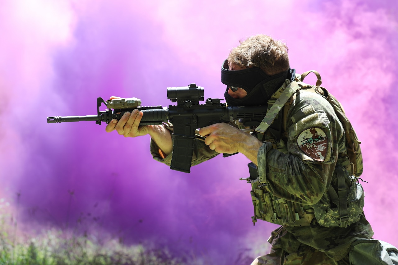 A soldier aims a weapon as purple smoke billows behind him.
