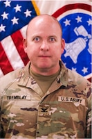 Soldier in uniform in front of flags.