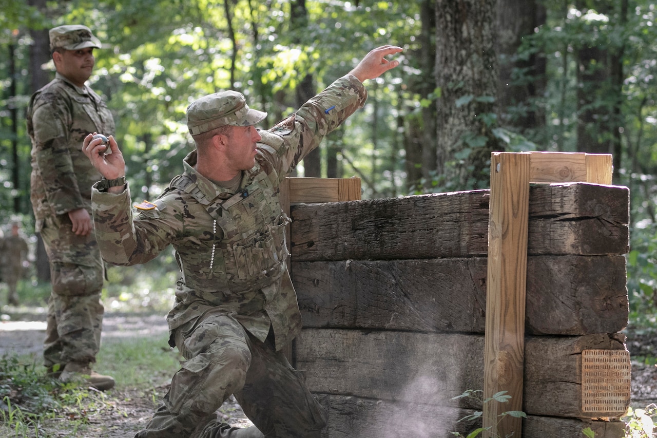 A soldier throws a grenade over a wood plank in a forested area.